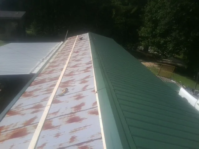 Old rusted panels beside newly installed green metal roofing — Wind Damage Roof Repair by Roofing Brothers in Waterford Works