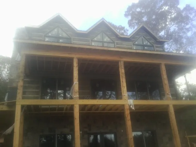 Dormers and porch framing on a large log home under construction — Roof Coating work by our crew in Waterford Works