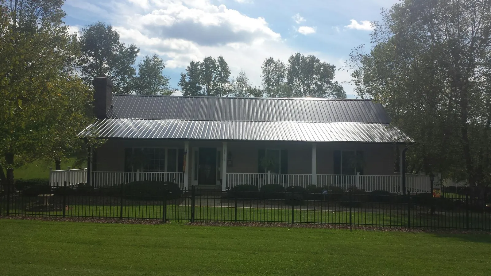 Gray metal roof on a brick ranch with a full width front porch — Gutter Guard Installation work by our crew in Waterford Works