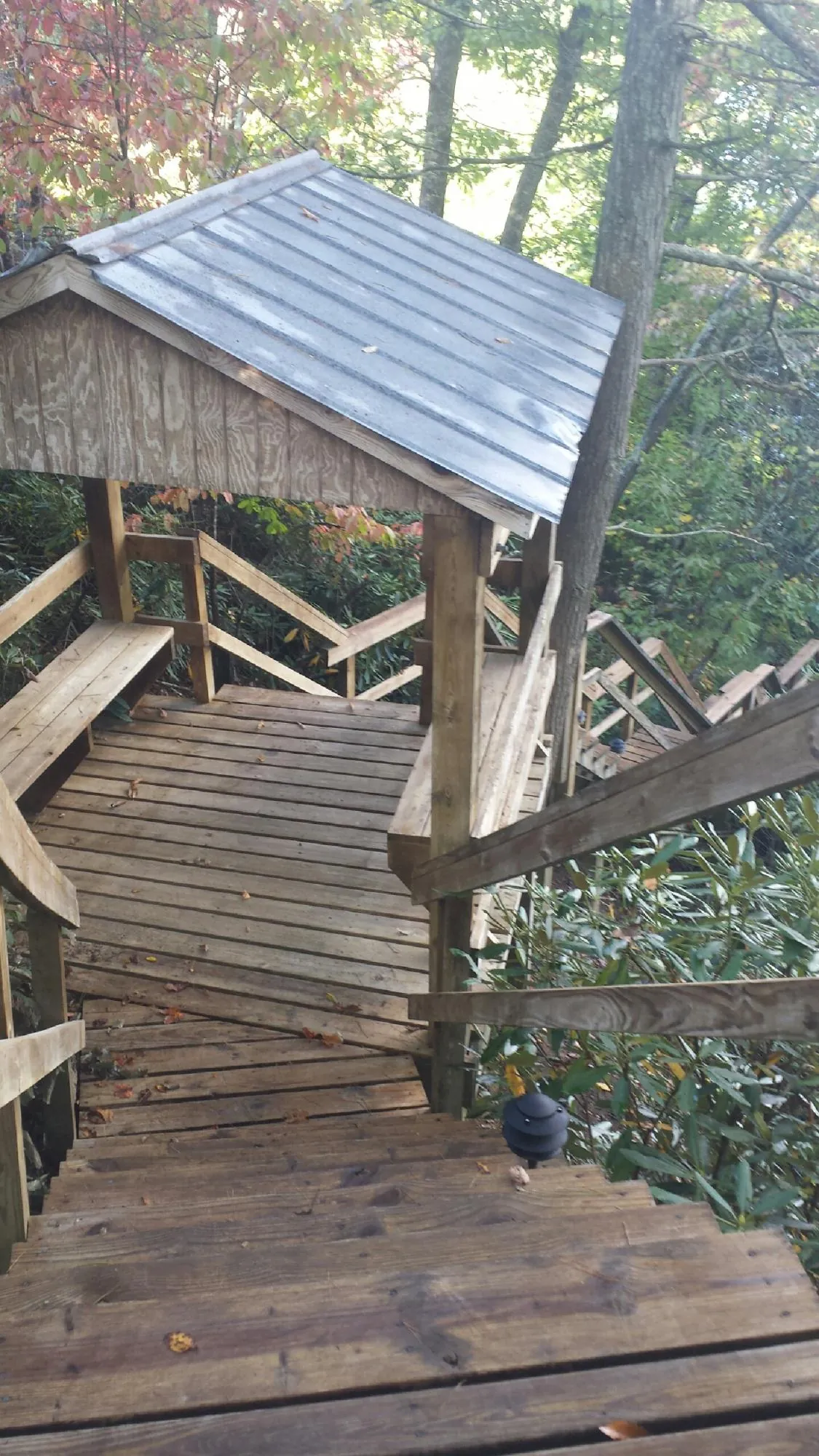 Metal roofed shelter over wooden steps on a wooded walkway — Skylight Repair & Installation work by our crew in Waterford Works