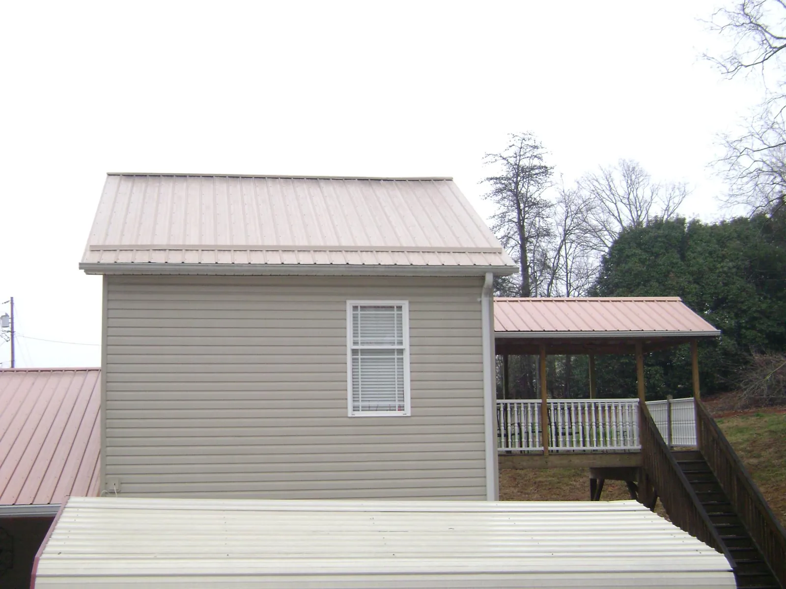 Tan metal roofs on a two story addition and attached porch, from a Roof Replacement job in Waterford Works