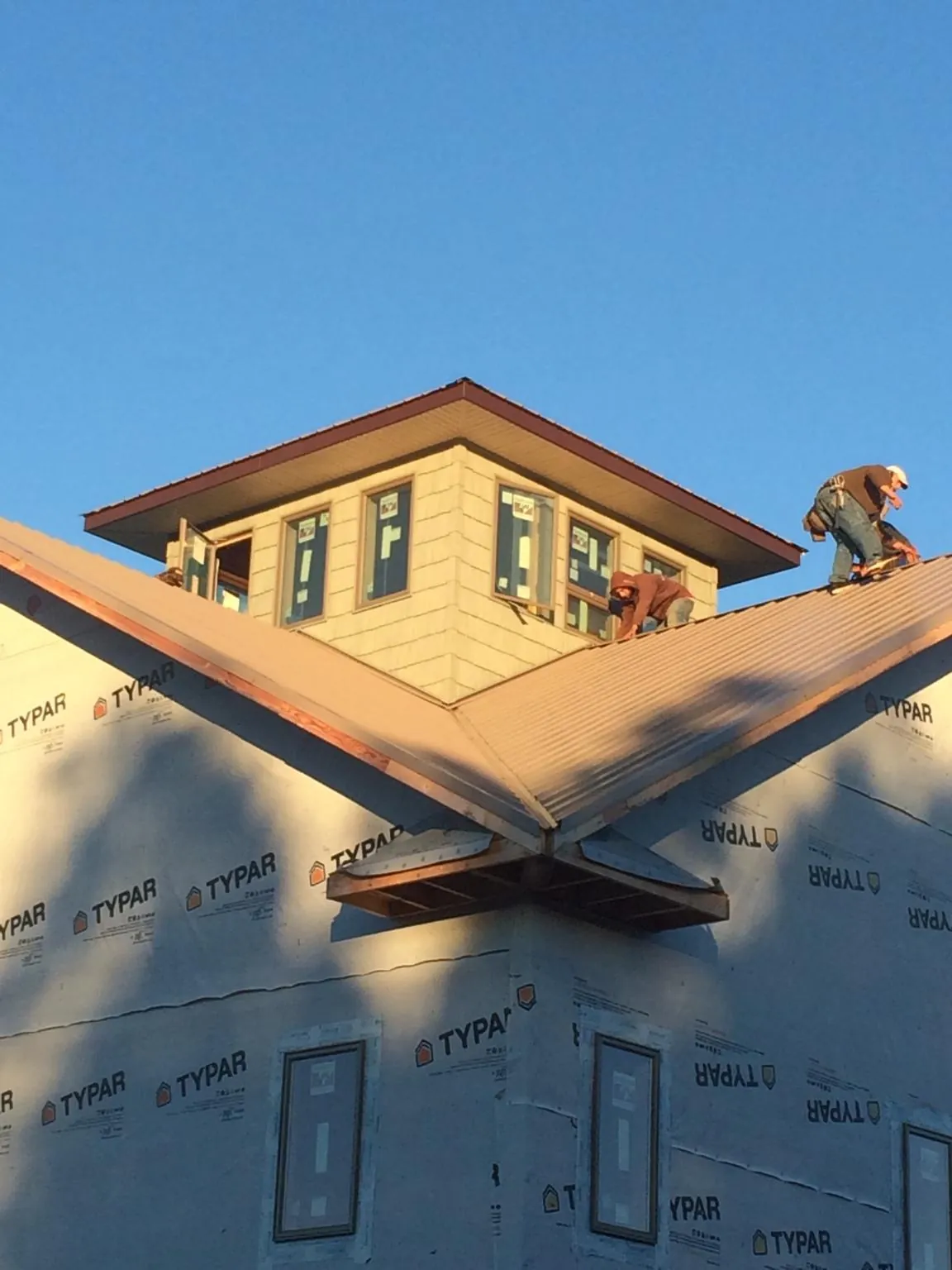 Roofers working around a rooftop cupola on a new metal roof at sunset — Roof Waterproofing in Waterford Works by Roofing Brothers